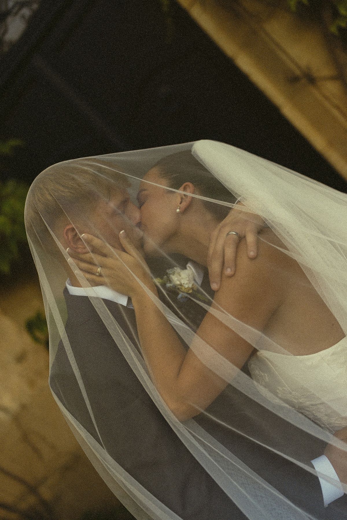 The couple share a kiss beneath the bride's sheer veil, which drapes over both of them.