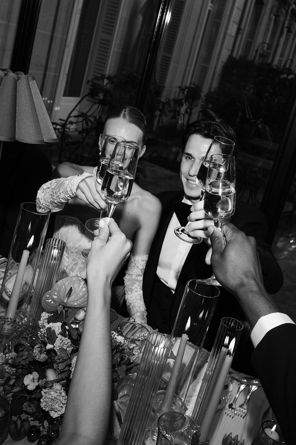 Black and white photo of the bride and groom toasting with guests at dinner