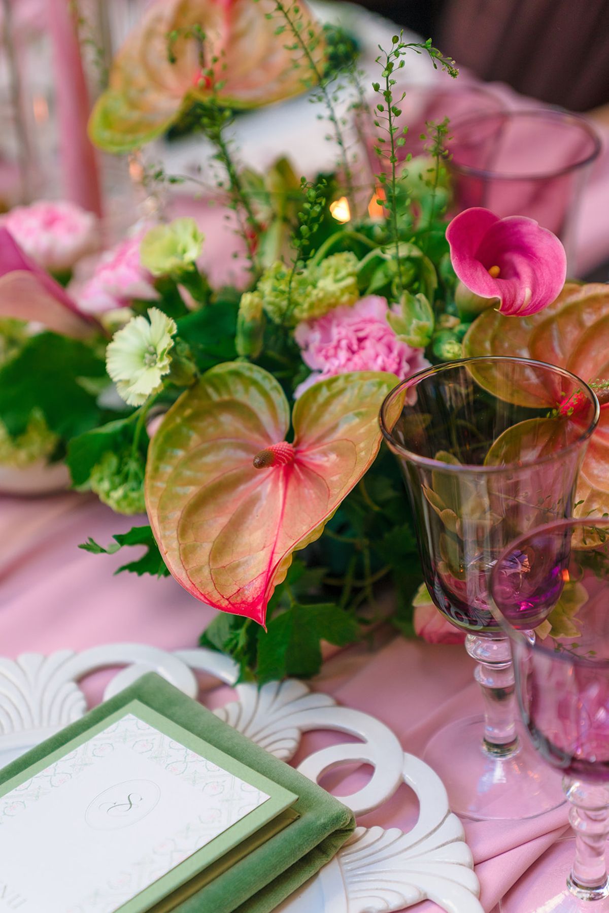 Centrepiece of anthuriums, calla lilies and carnations on the pink dinner table
