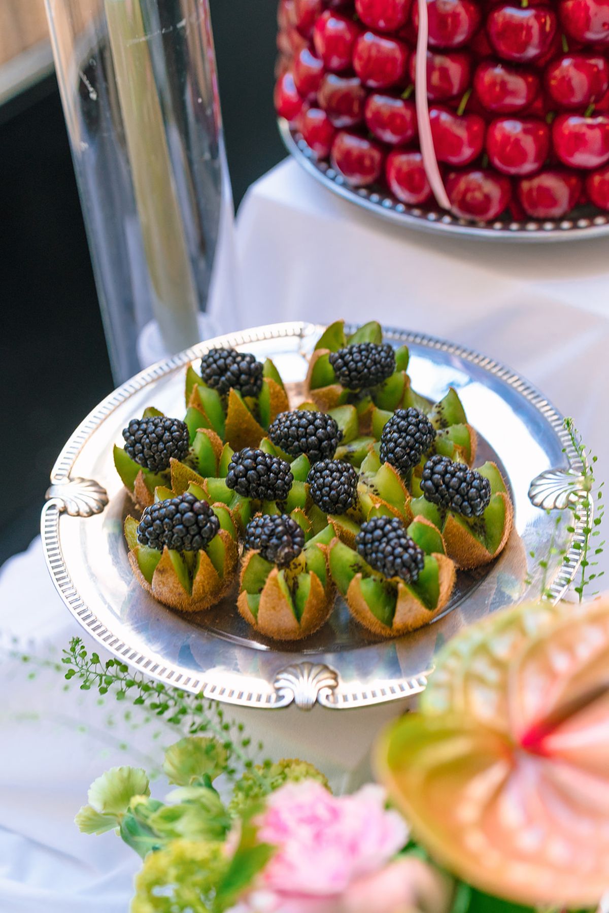 Blackberry tartlets on a silver platter beside the cherry tower