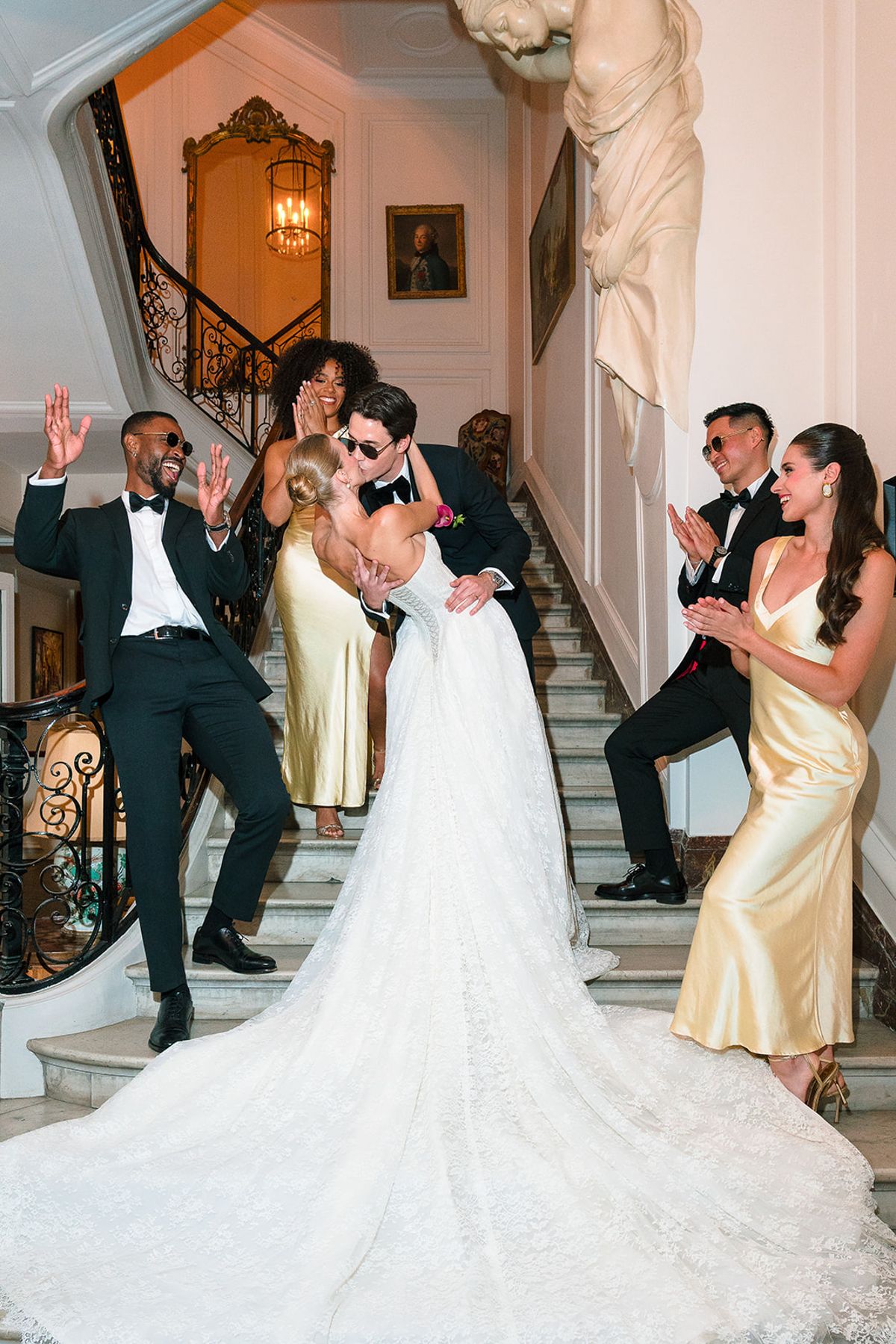 Bridesmaids and groomsmen cheering the couple on the grand staircase at Hôtel Alfred Sommier