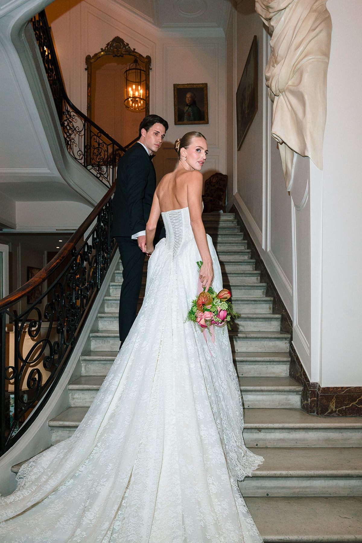 Bride looking back over her shoulder on the grand stone staircase with the groom, Hôtel Alfred Sommier