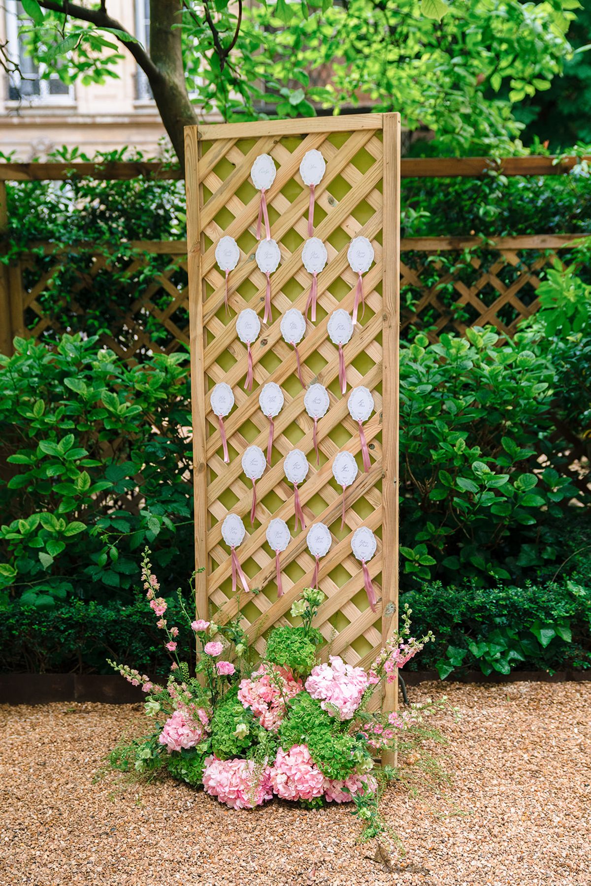 Trellis escort card display framed with pink hydrangeas in the garden at Hôtel Alfred Sommier
