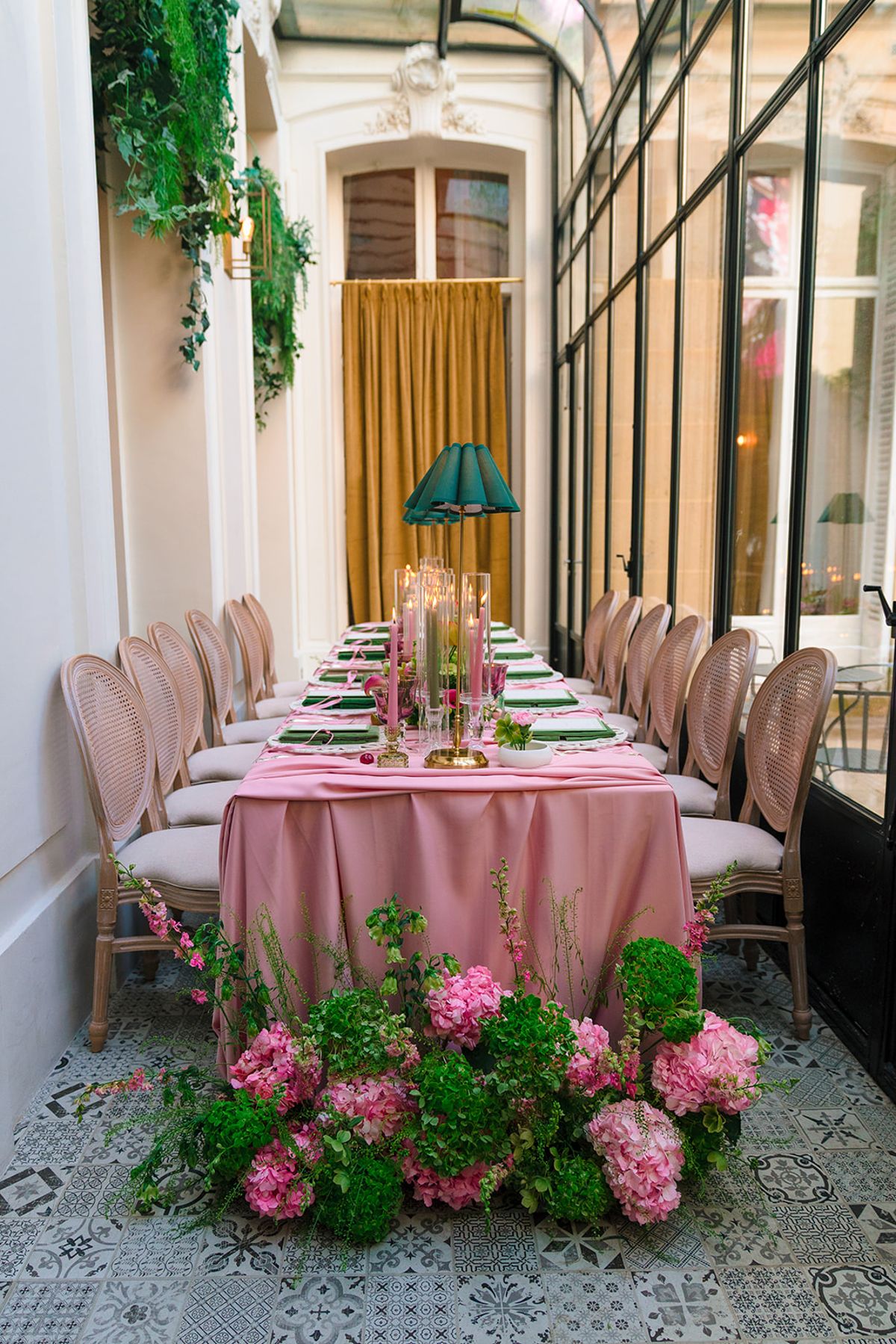 Dinner table dressed in pink linen with hydrangeas in a glass-walled room at Hôtel Alfred Sommier