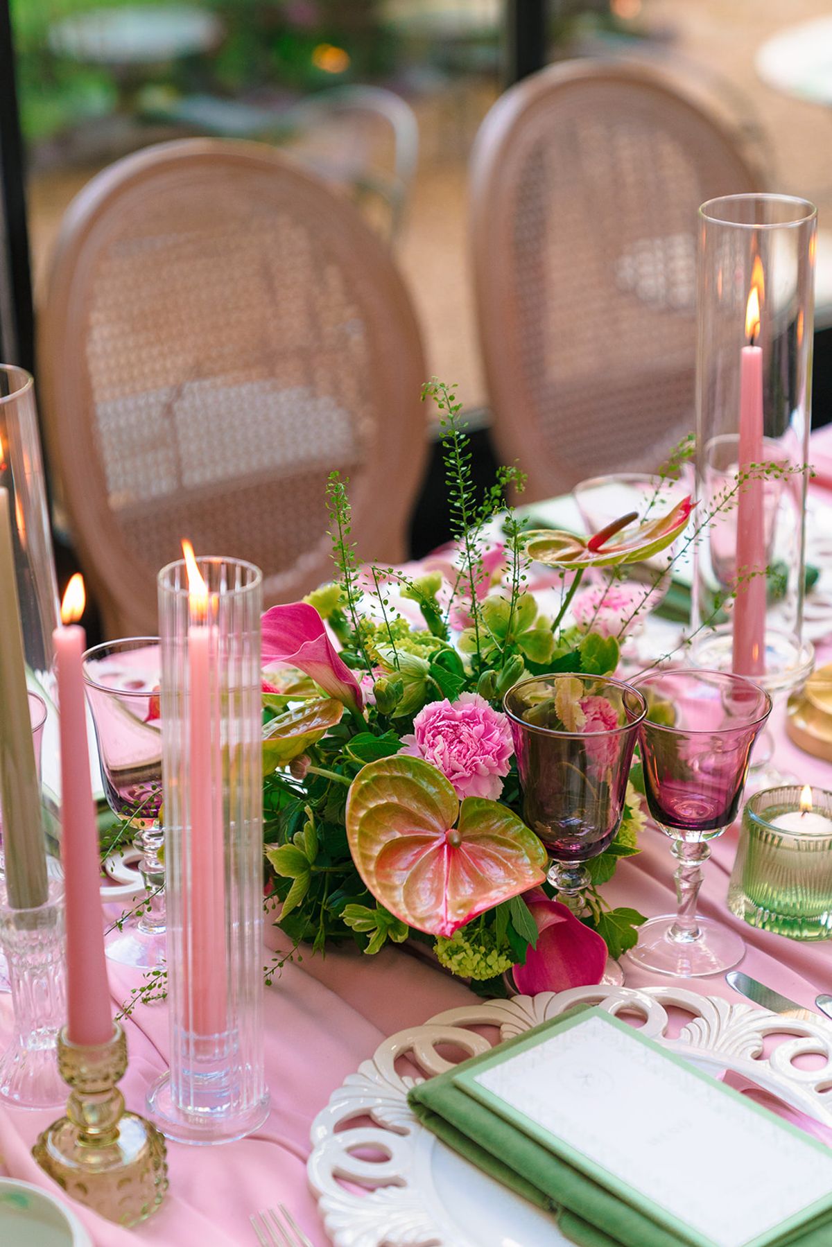Candlelit centrepiece of anthuriums and pink florals with pink taper candles