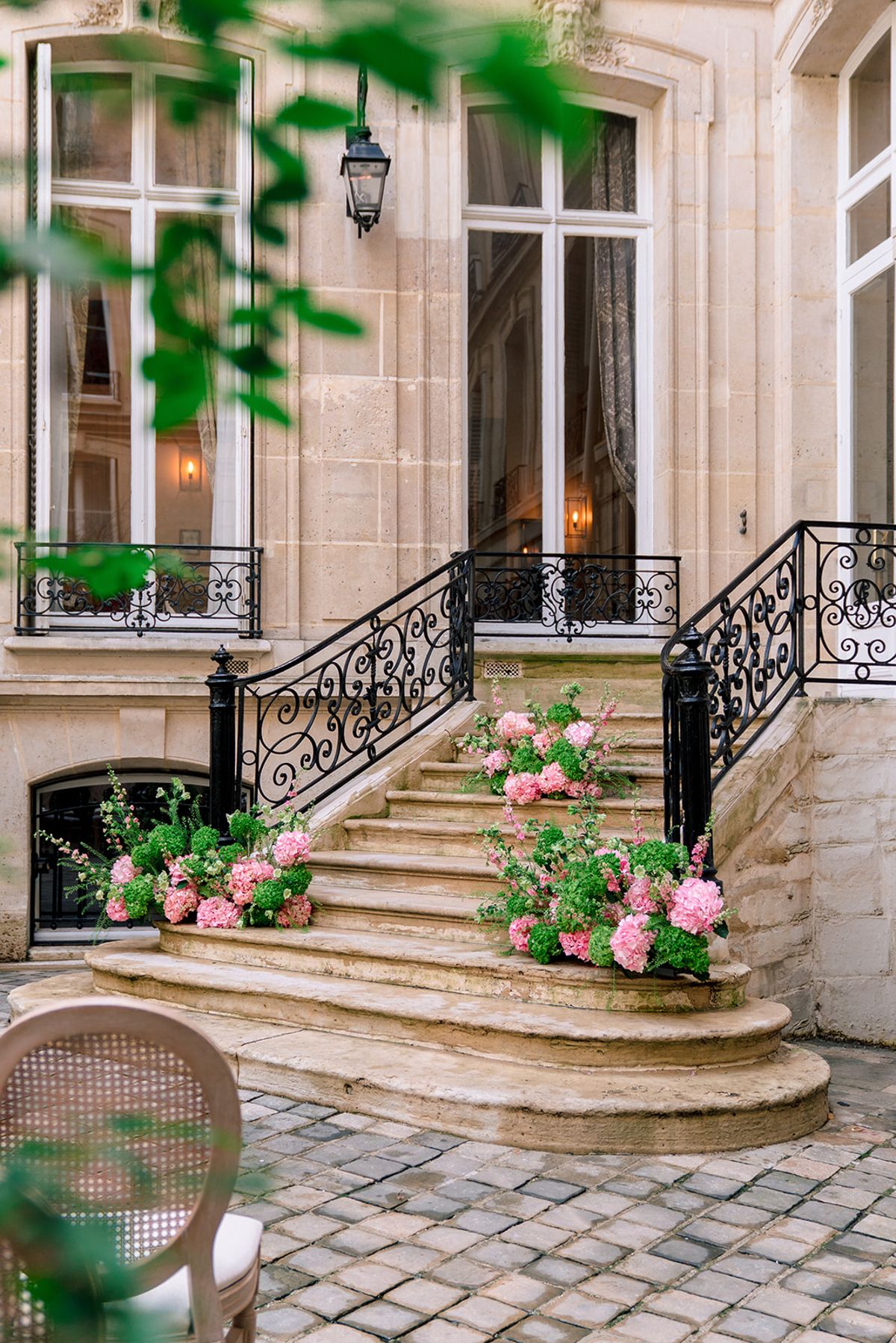 Stone courtyard and double staircase dressed with pink hydrangeas at Hôtel Alfred Sommier