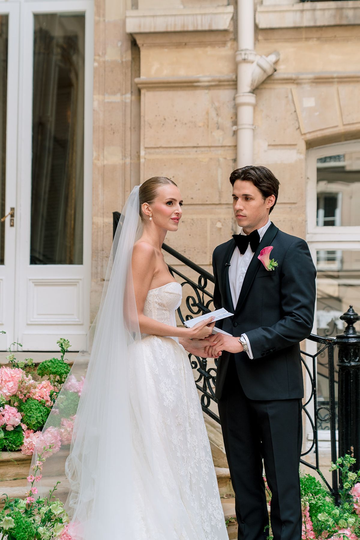 Bride and groom holding hands as they read vows in the courtyard at Hôtel Alfred Sommier