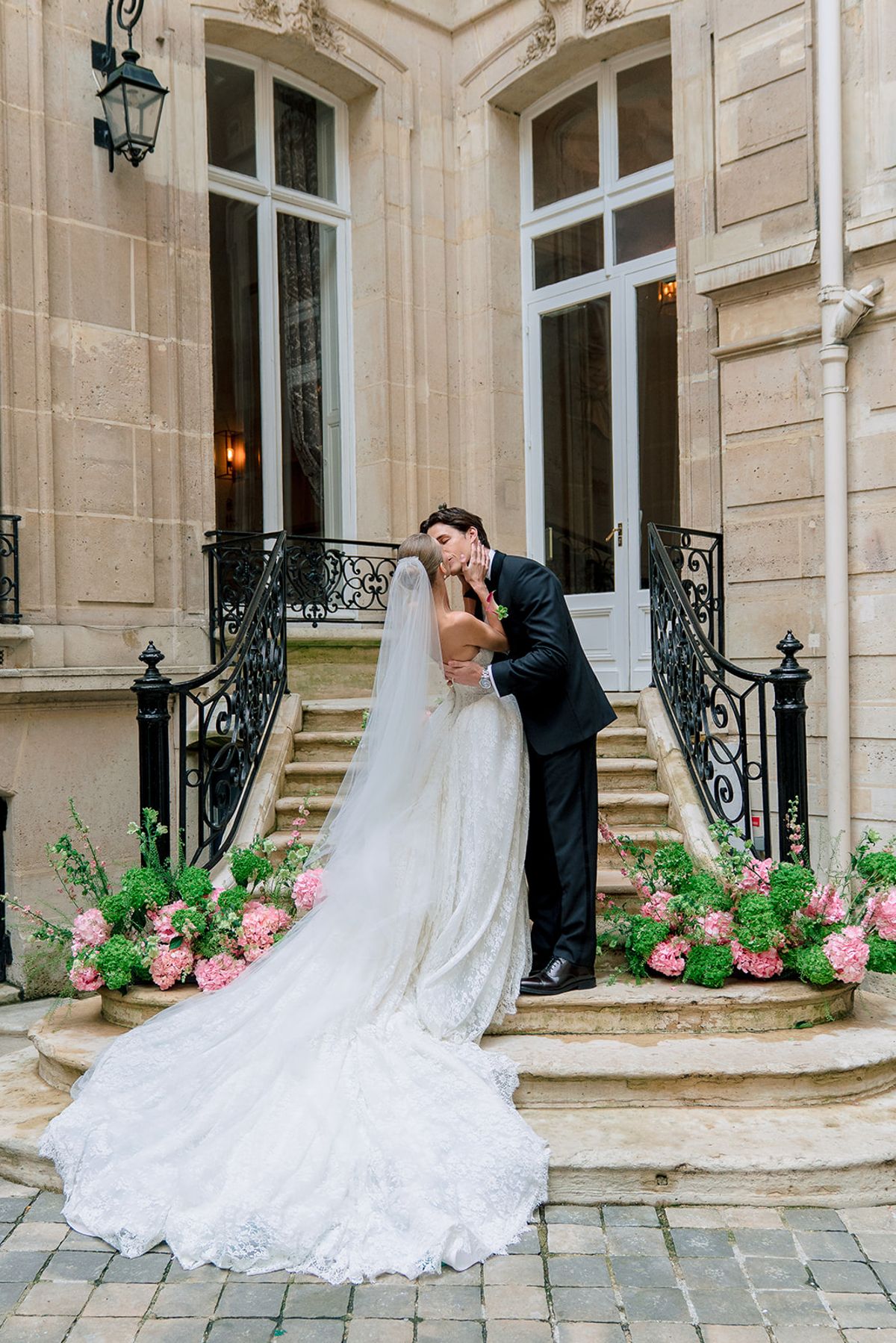 Bride and groom kissing on the courtyard steps framed by pink hydrangeas at Hôtel Alfred Sommier