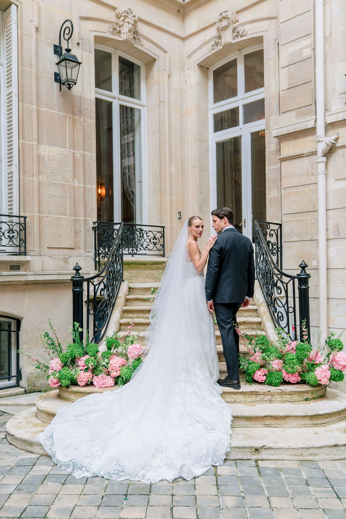 Bride and groom walking up the courtyard steps with her veil and train behind, Hôtel Alfred Sommier