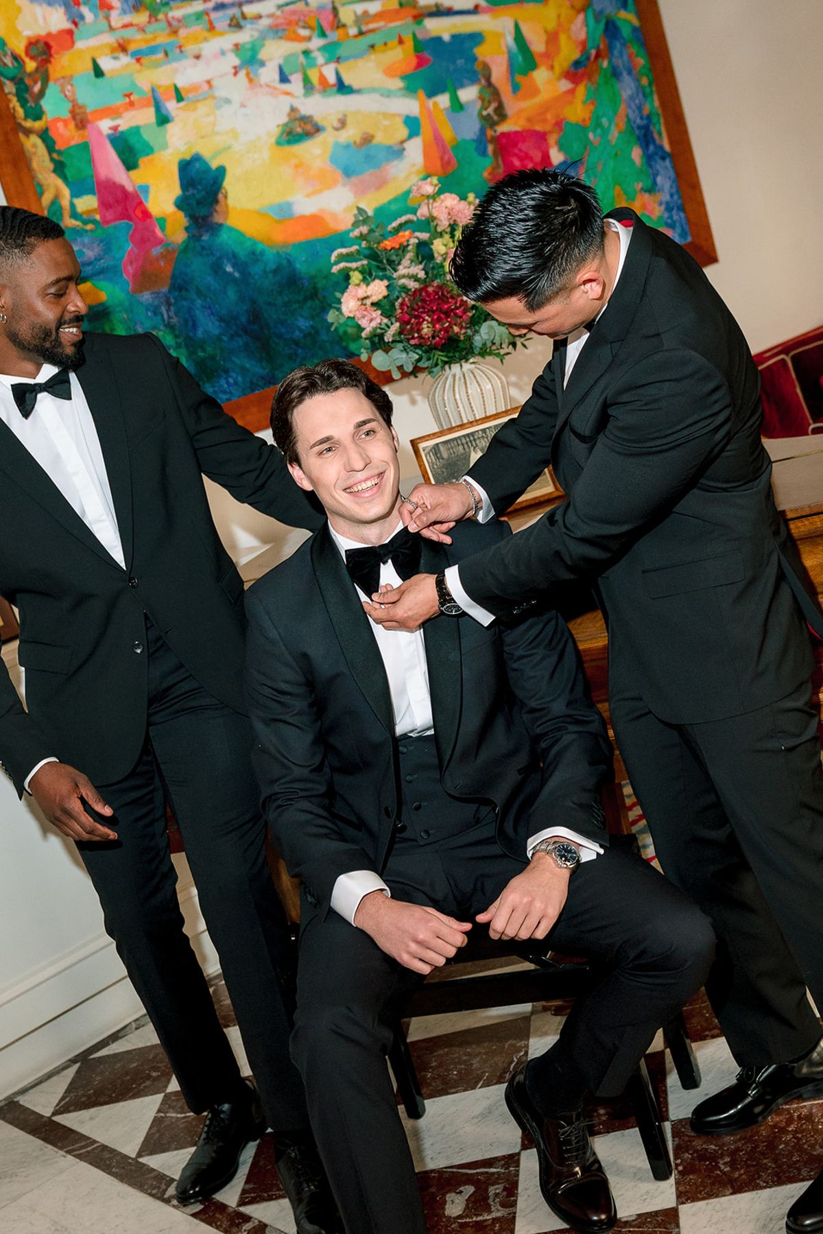 Groomsmen fixing the groom's bow tie in a salon at Hôtel Alfred Sommier