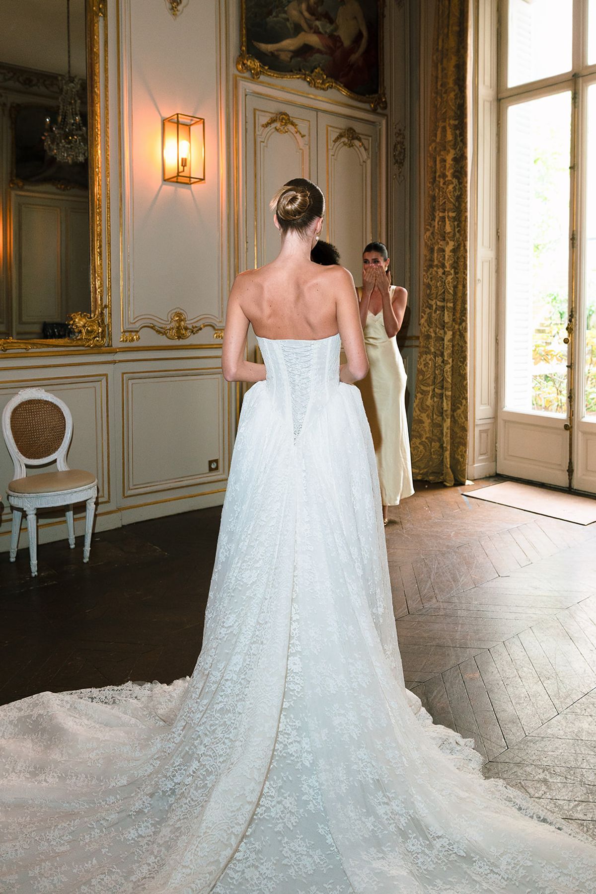 Bride seen from behind in her lace gown and train in a gilded salon at Hôtel Alfred Sommier