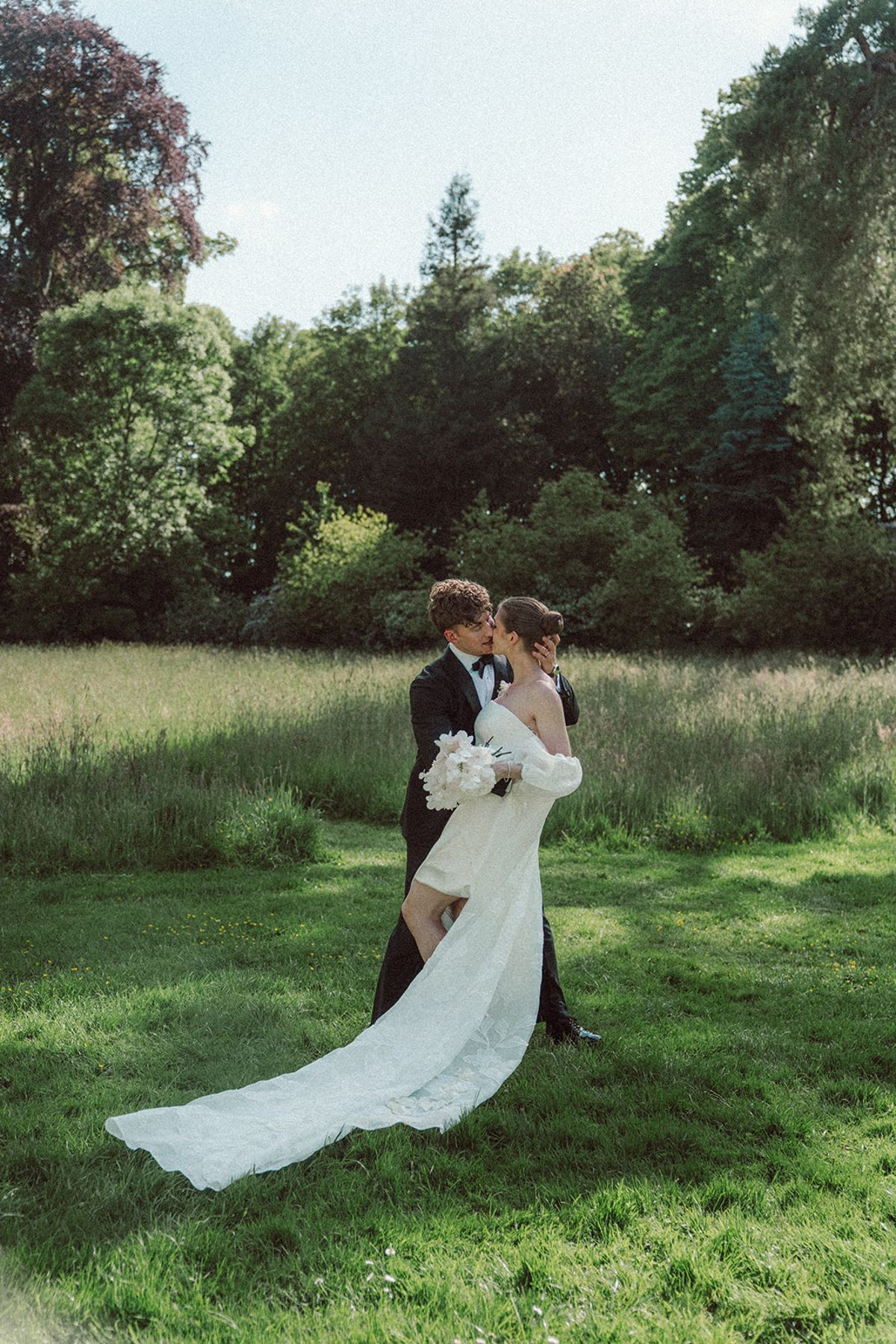 Bride and groom kissing in a field of tall grass