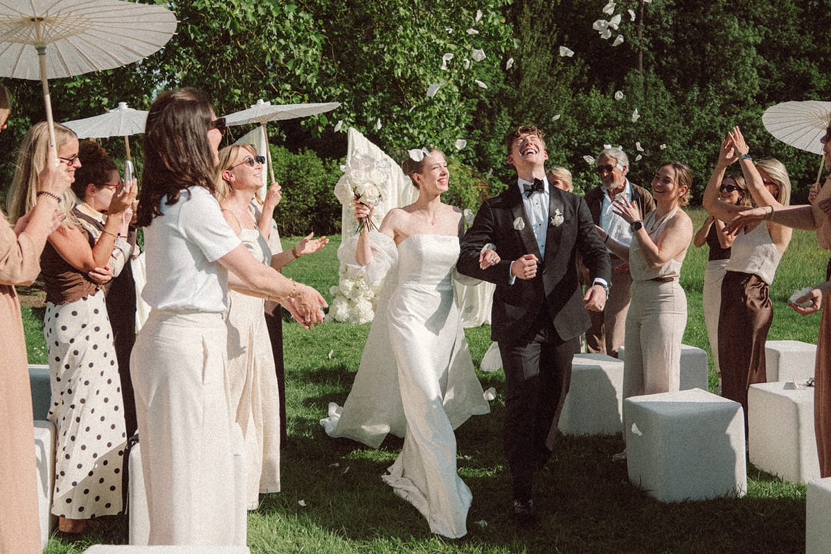 Guests cheering as the couple exits the ceremony, wide shot