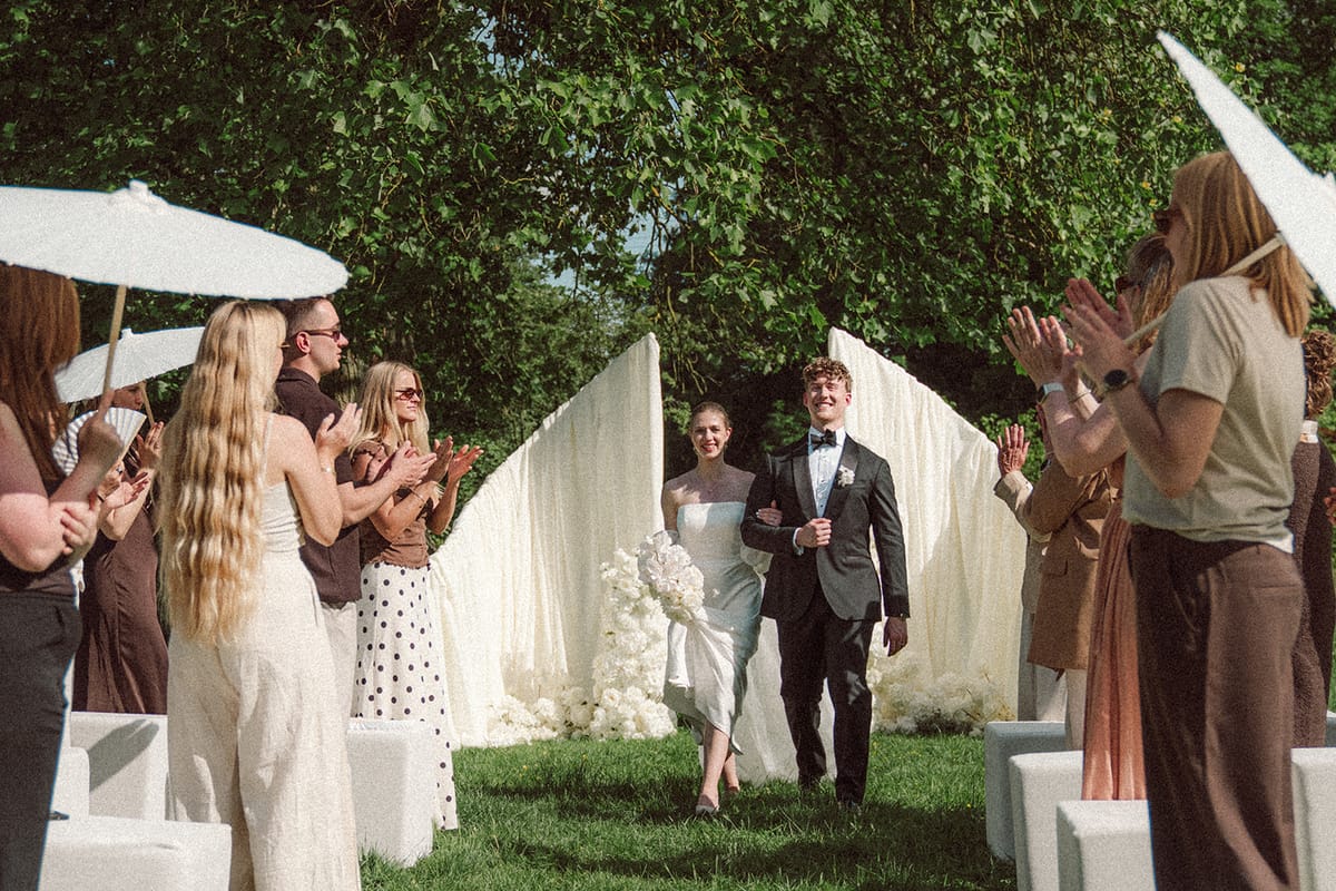 Guests applauding as the couple walks down the ceremony aisle