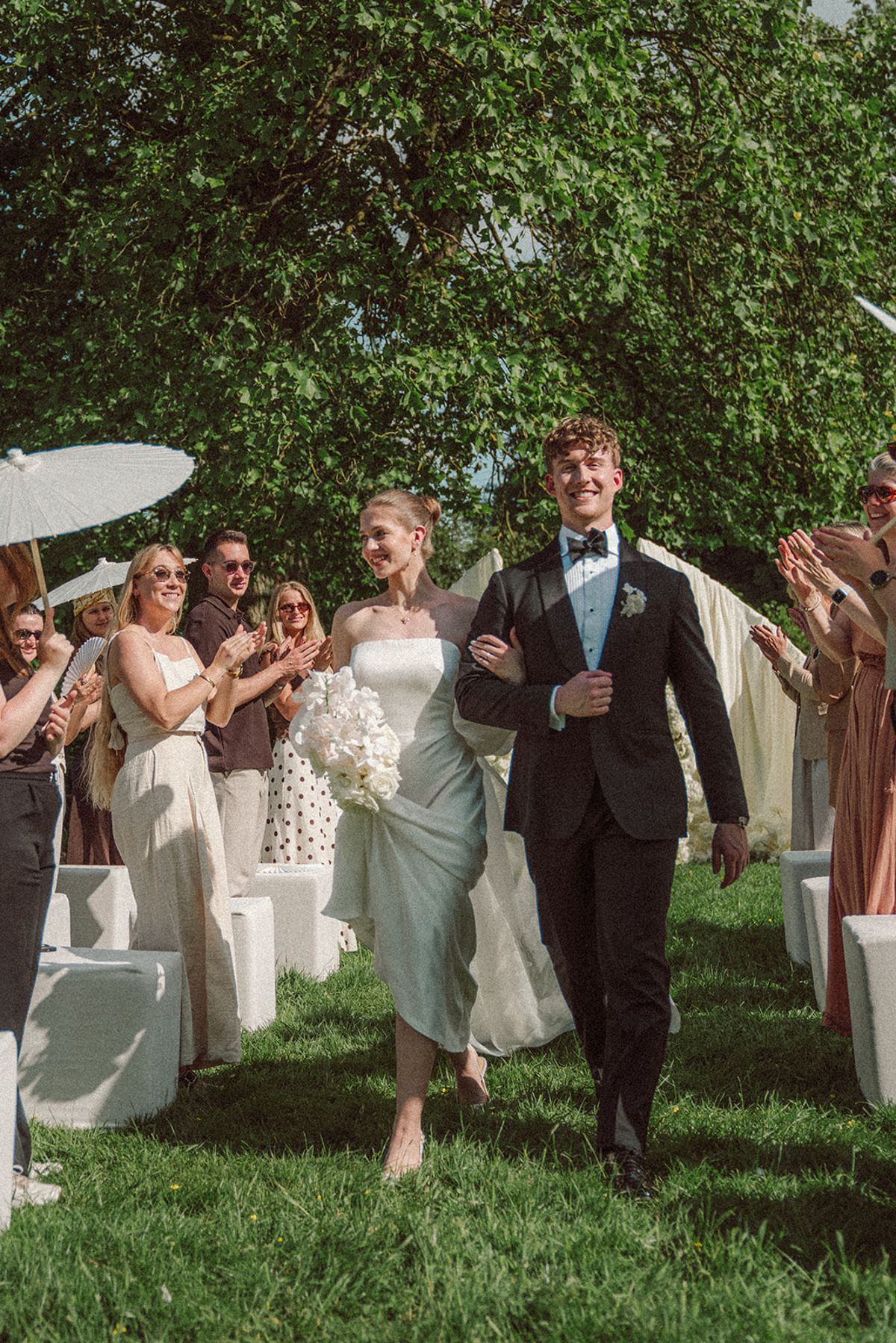 Guests applauding as the couple walks down the ceremony aisle
