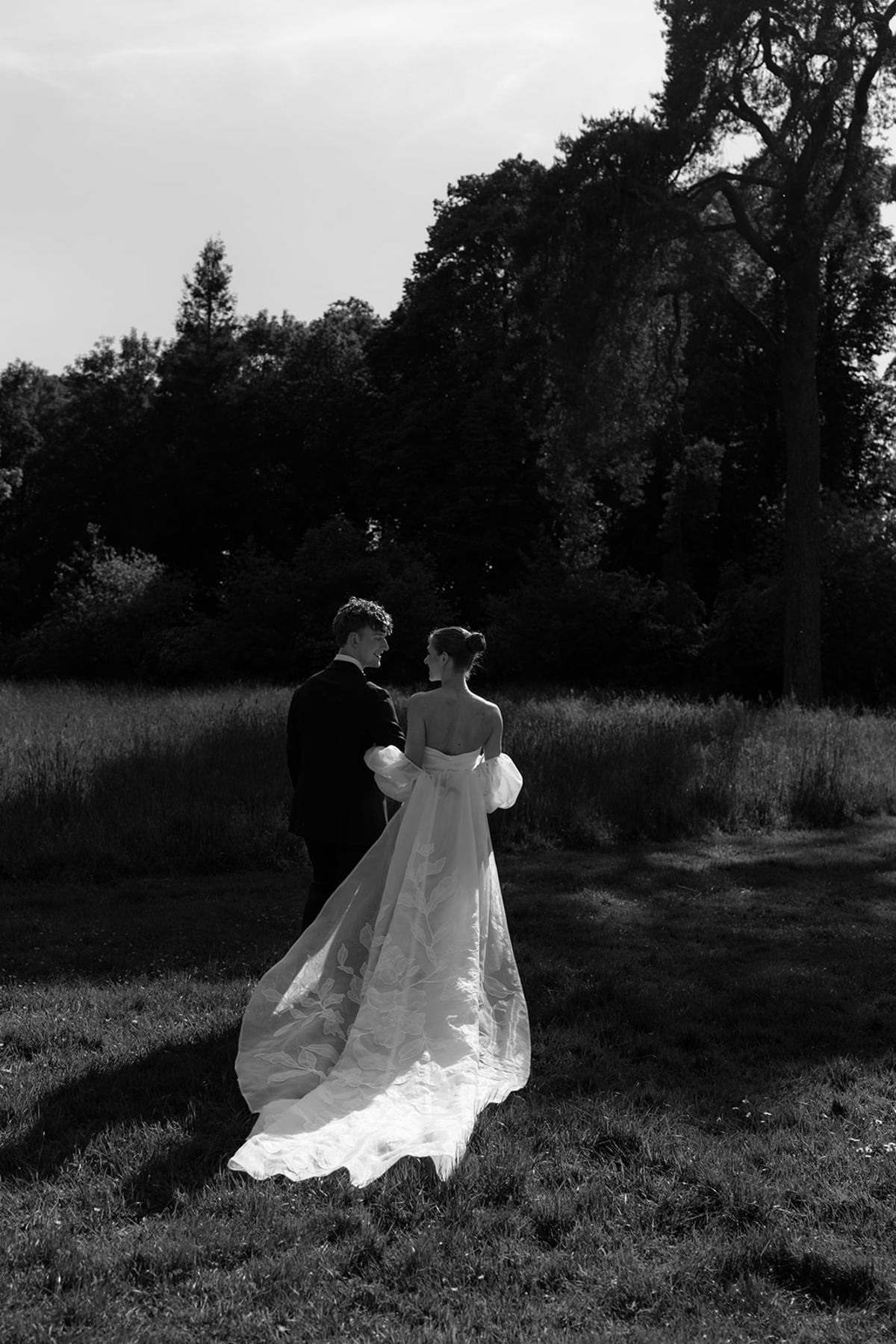 Bride and groom walking away hand in hand, black and white
