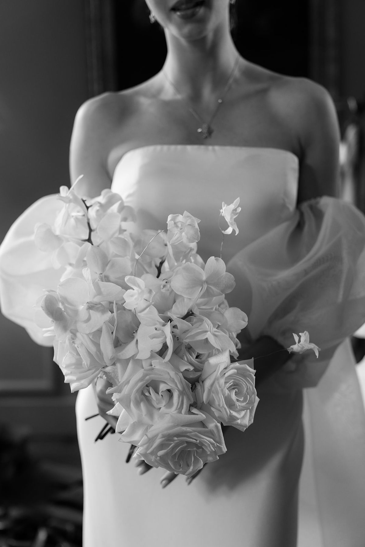 Close-up of the bridal bouquet against the bride's dress, black and white