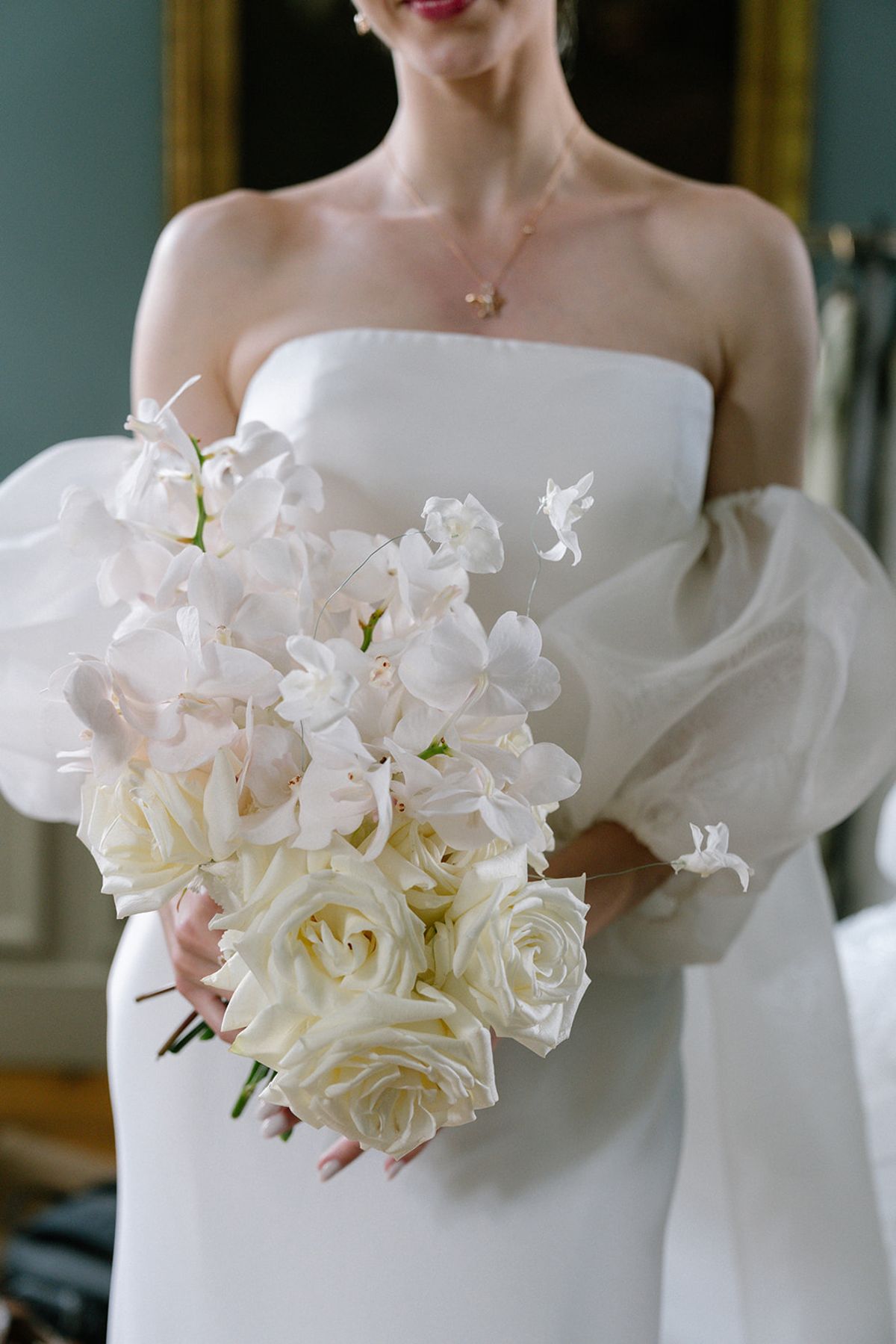 Bride holding a white rose and orchid bouquet, cropped detail