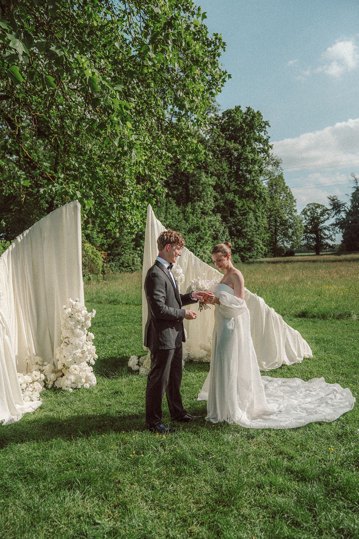 Bride and groom exchanging vows at a white draped ceremony arch