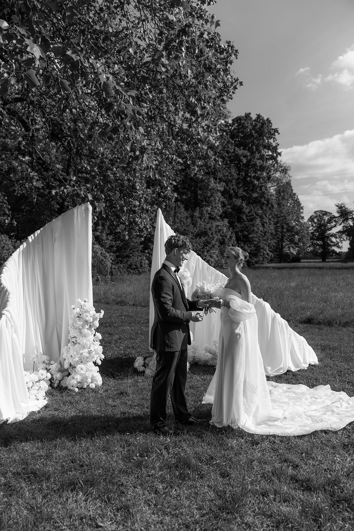 Bride and groom exchanging vows at the ceremony arch, black and white