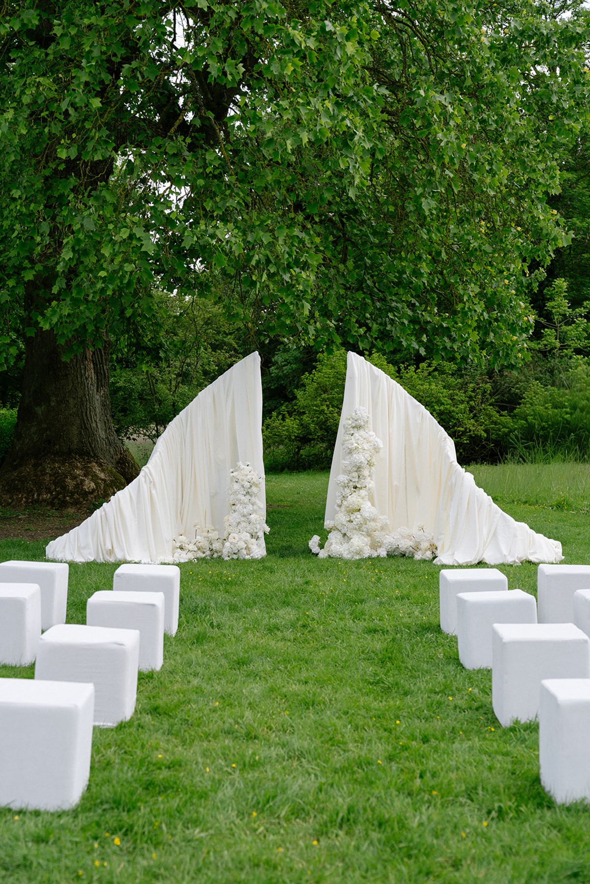 The empty ceremony arch and white cube seating on the lawn