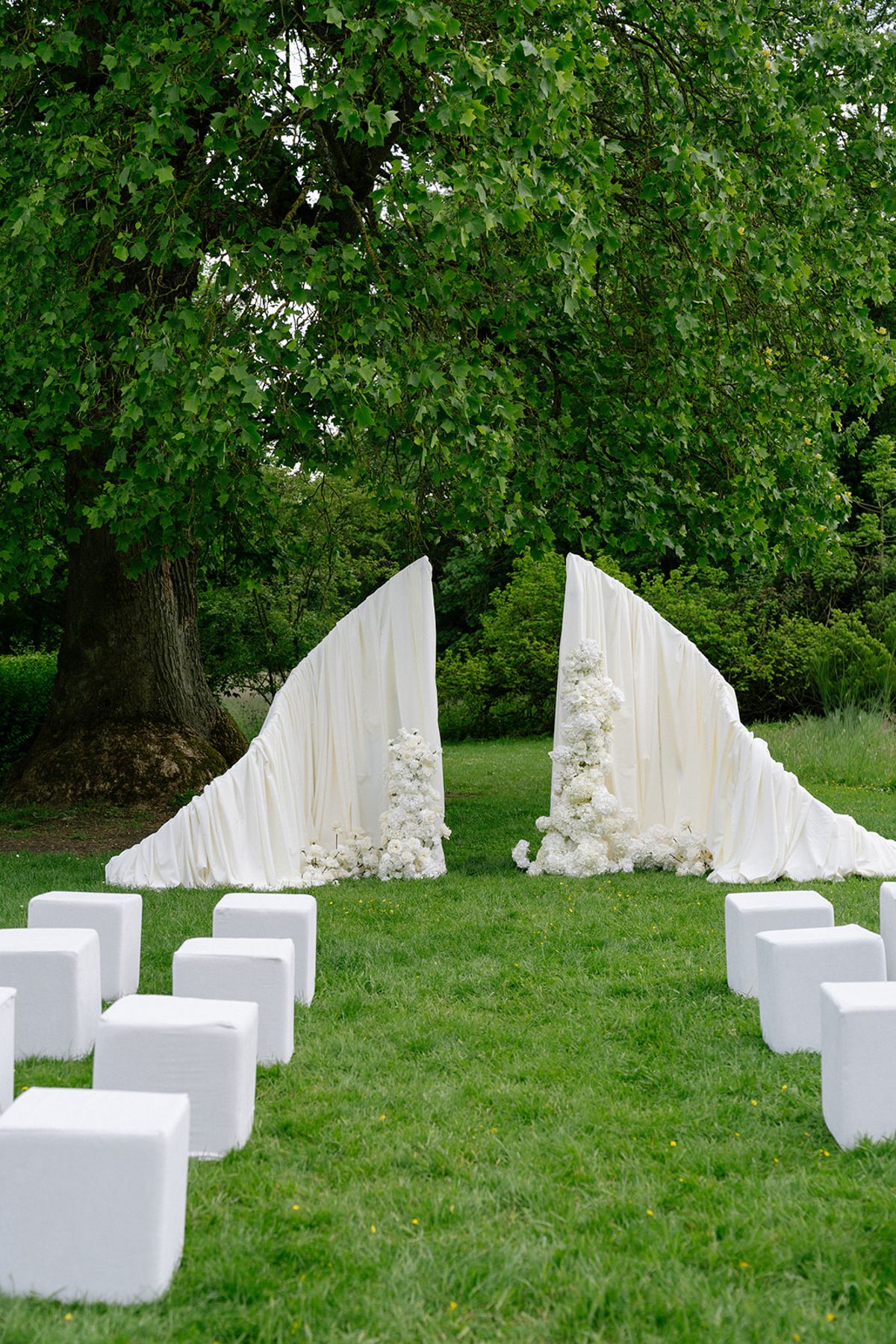 The empty ceremony arch with white floral draping, before guests arrive