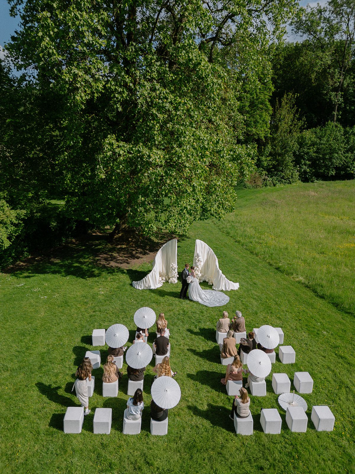 Aerial view of the ceremony lawn with white cube seating and floral arch