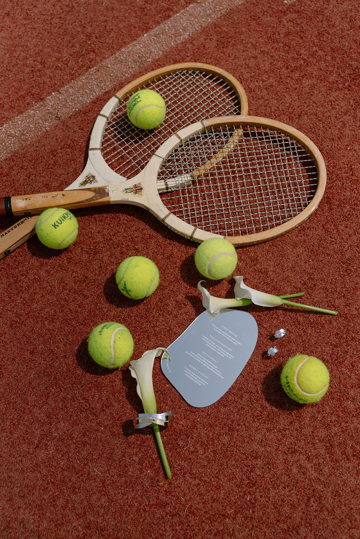 Vintage tennis rackets, balls and a menu card laid out on the court