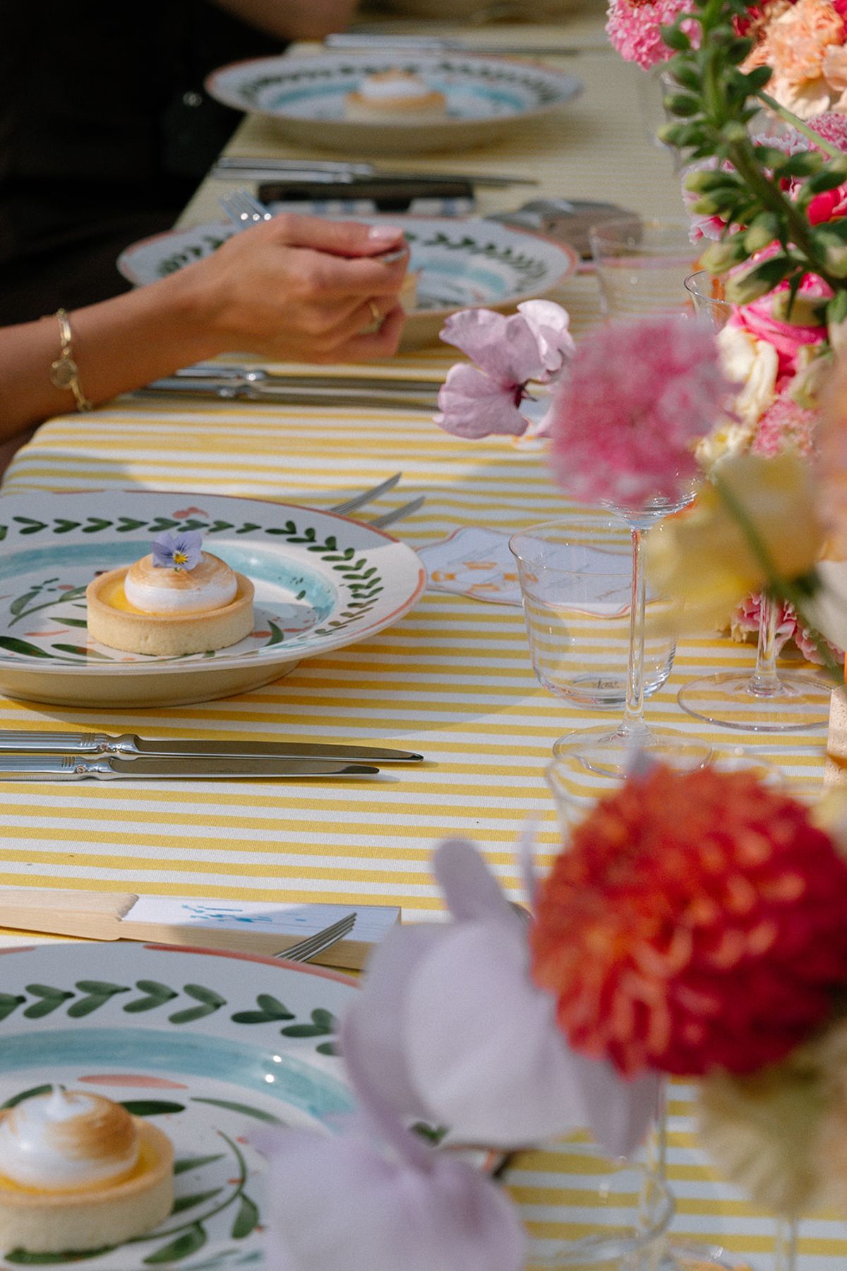 Yellow striped table setting with a dessert plate and dahlias