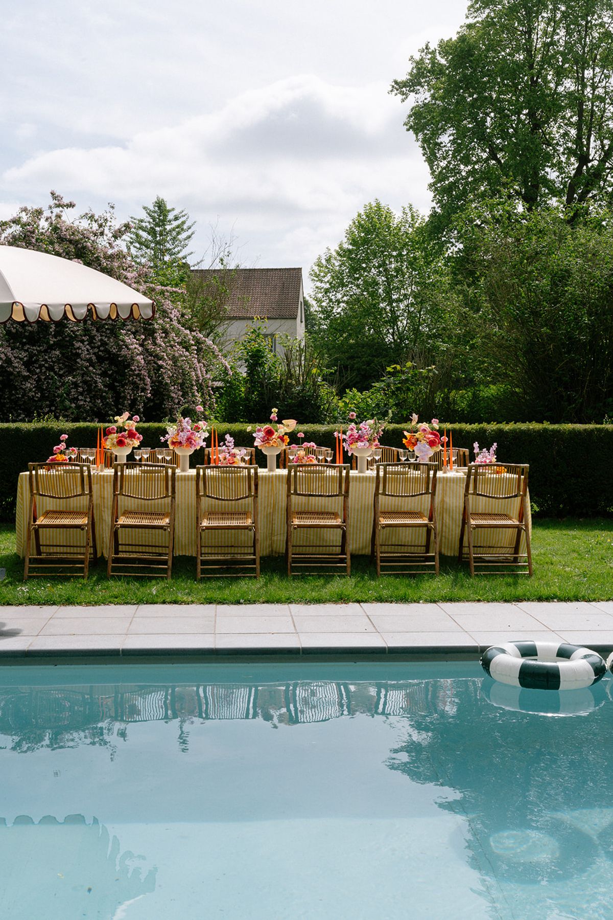 Long poolside reception table set with gold chairs and a colourful floral runner