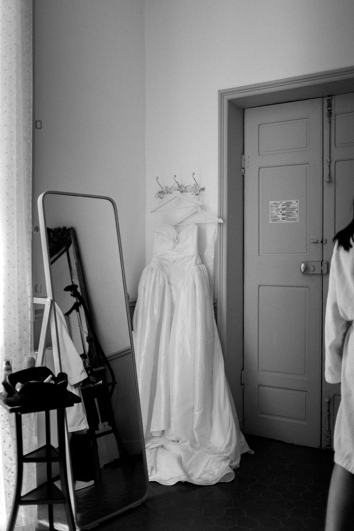 Clara's wedding dress hangs in the room before she puts it on, captured in black and white