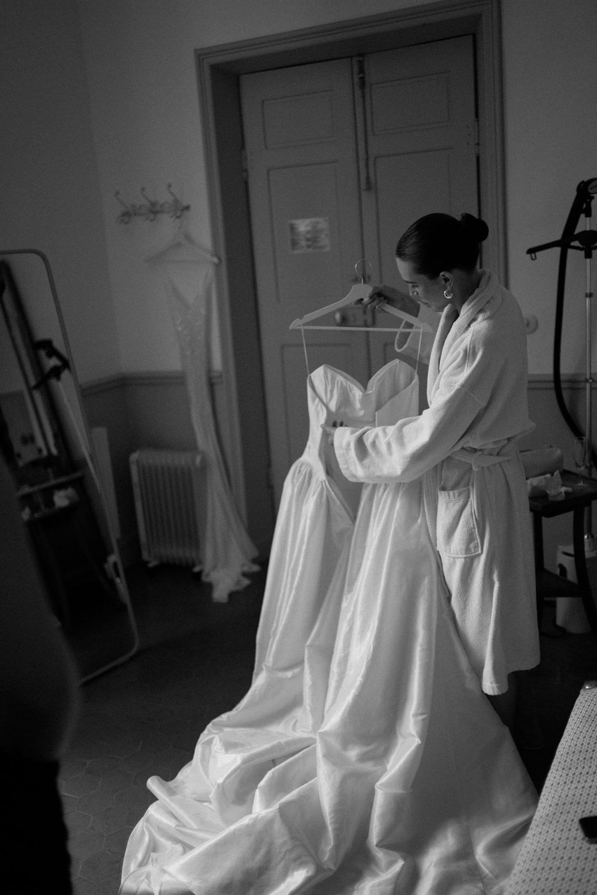 Clara's wedding dress hangs by a window, captured in black and white