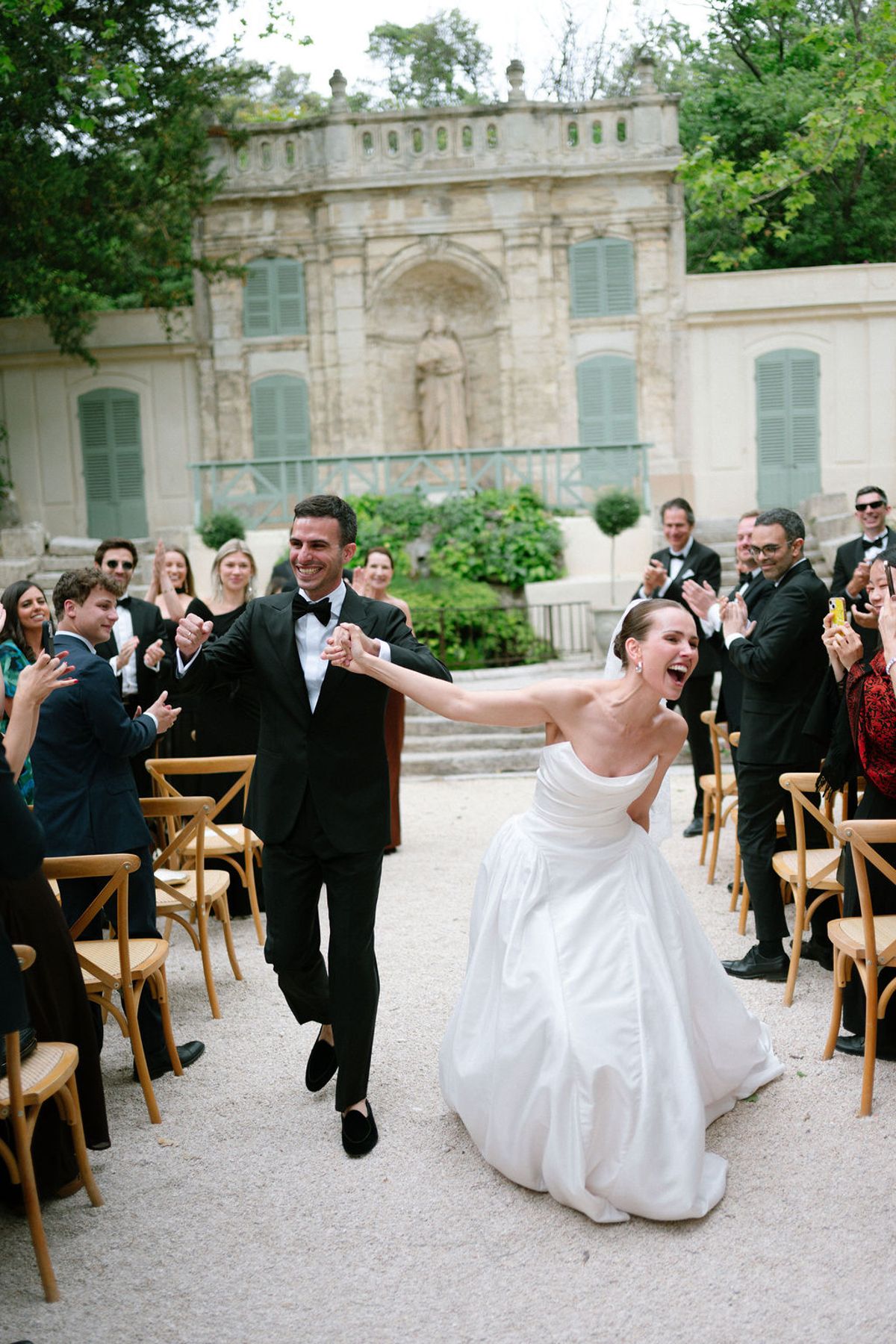 Clara and Constantin cheer with arms raised as guests applaud around them