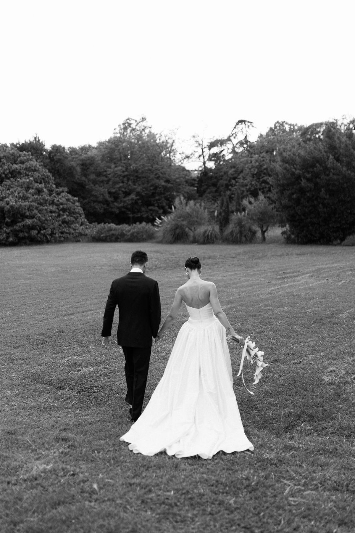 Clara and Constantin walk hand in hand across the lawn, seen from behind
