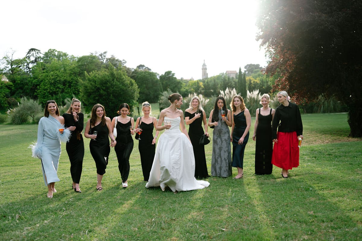 Clara and her bridesmaids walk together across the lawn in the late afternoon light