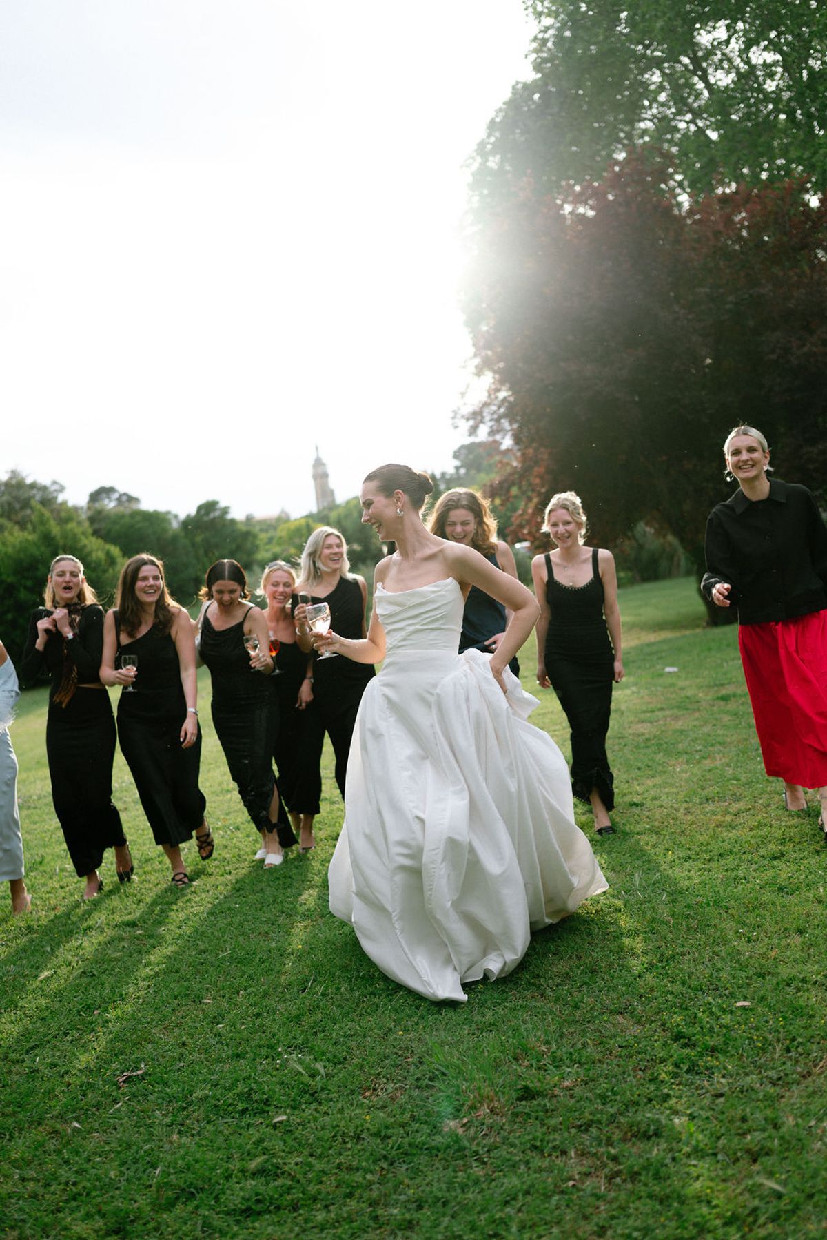 Clara walks with her bridesmaids across the lawn