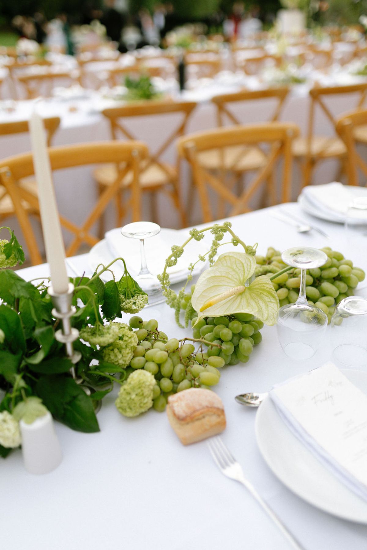 A candlelit table setting with green grapes and white florals