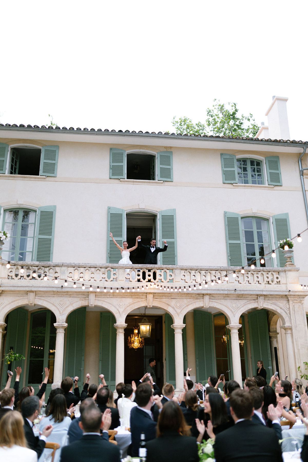 The shuttered facade of Bastide de Toursainte with the bridal party gathered on the balcony above