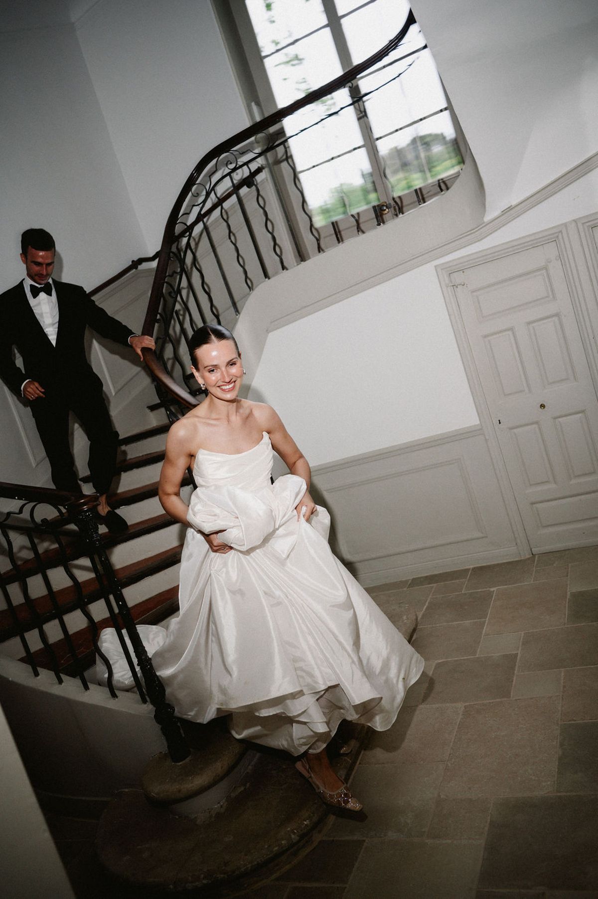 Clara descends the staircase at Bastide de Toursainte holding her wedding dress before the ceremony