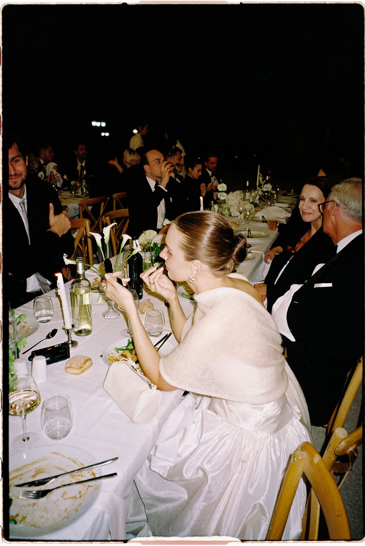 Guests seated at a long dinner table, with a violinist performing beside them
