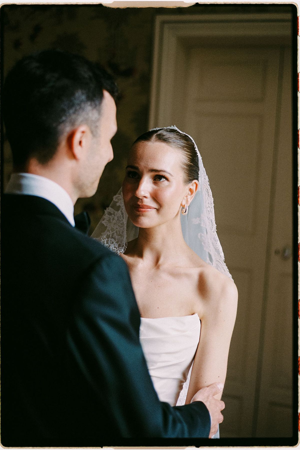 Clara and Constantin stand face to face, her veil framing the moment