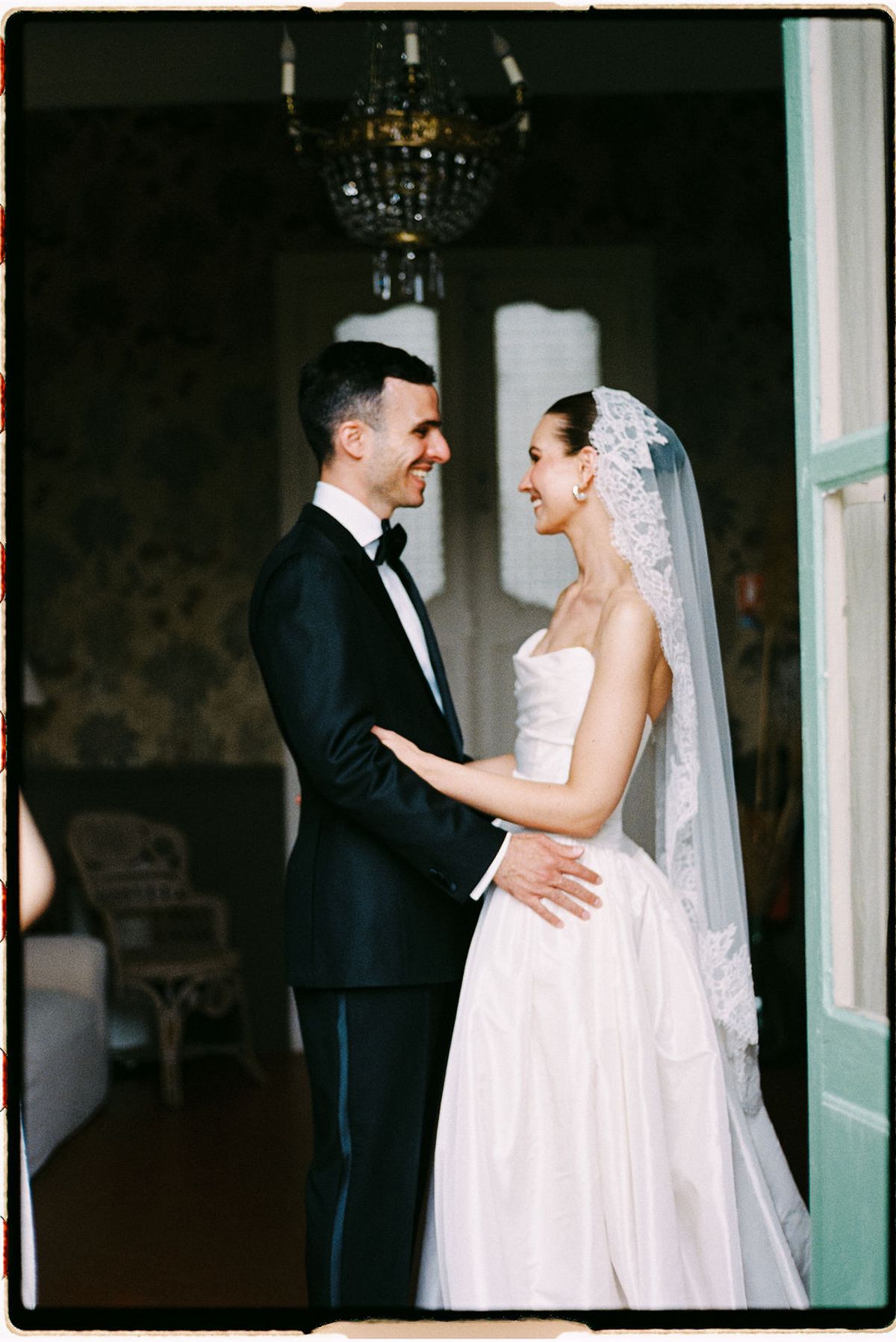 Clara and Constantin stand close together indoors, her veil visible