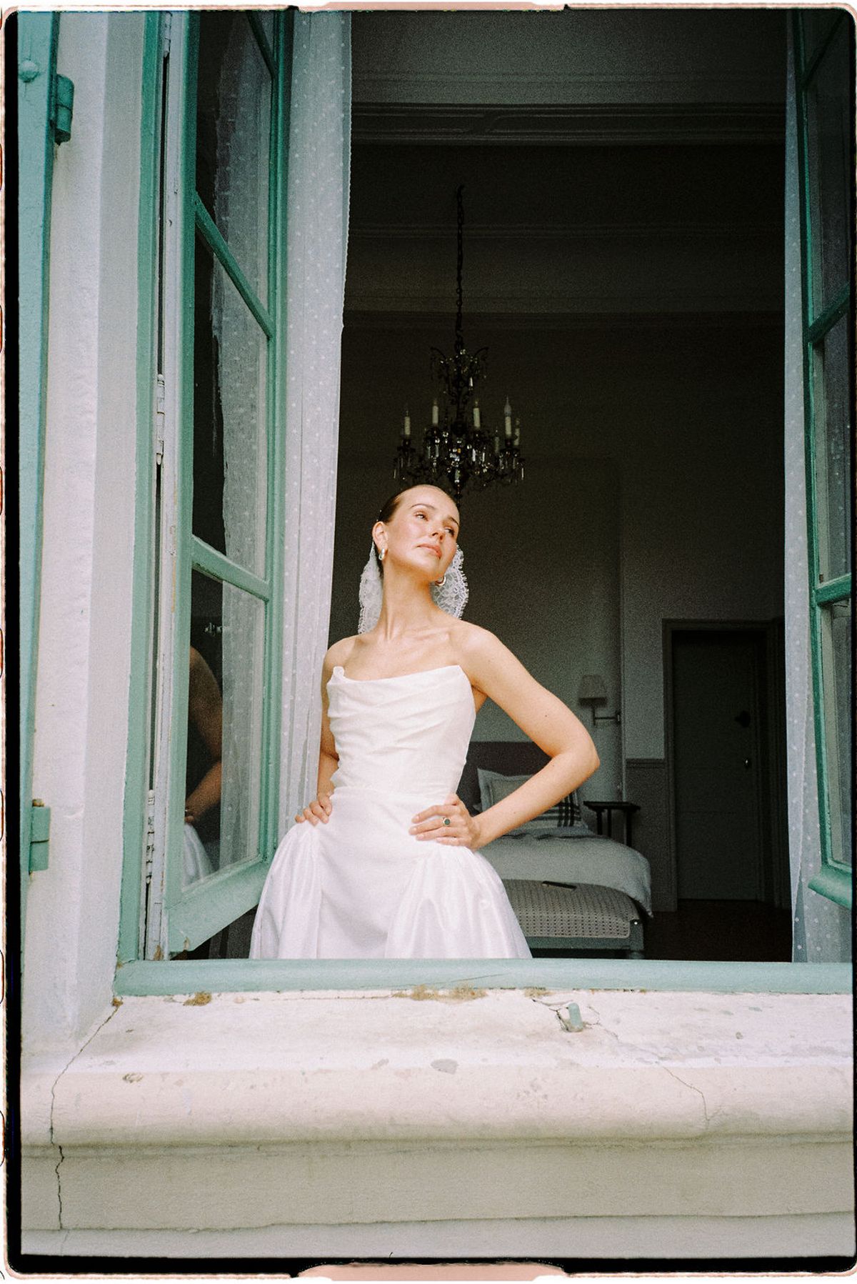 Clara stands by an open window during preparations, hand on hip