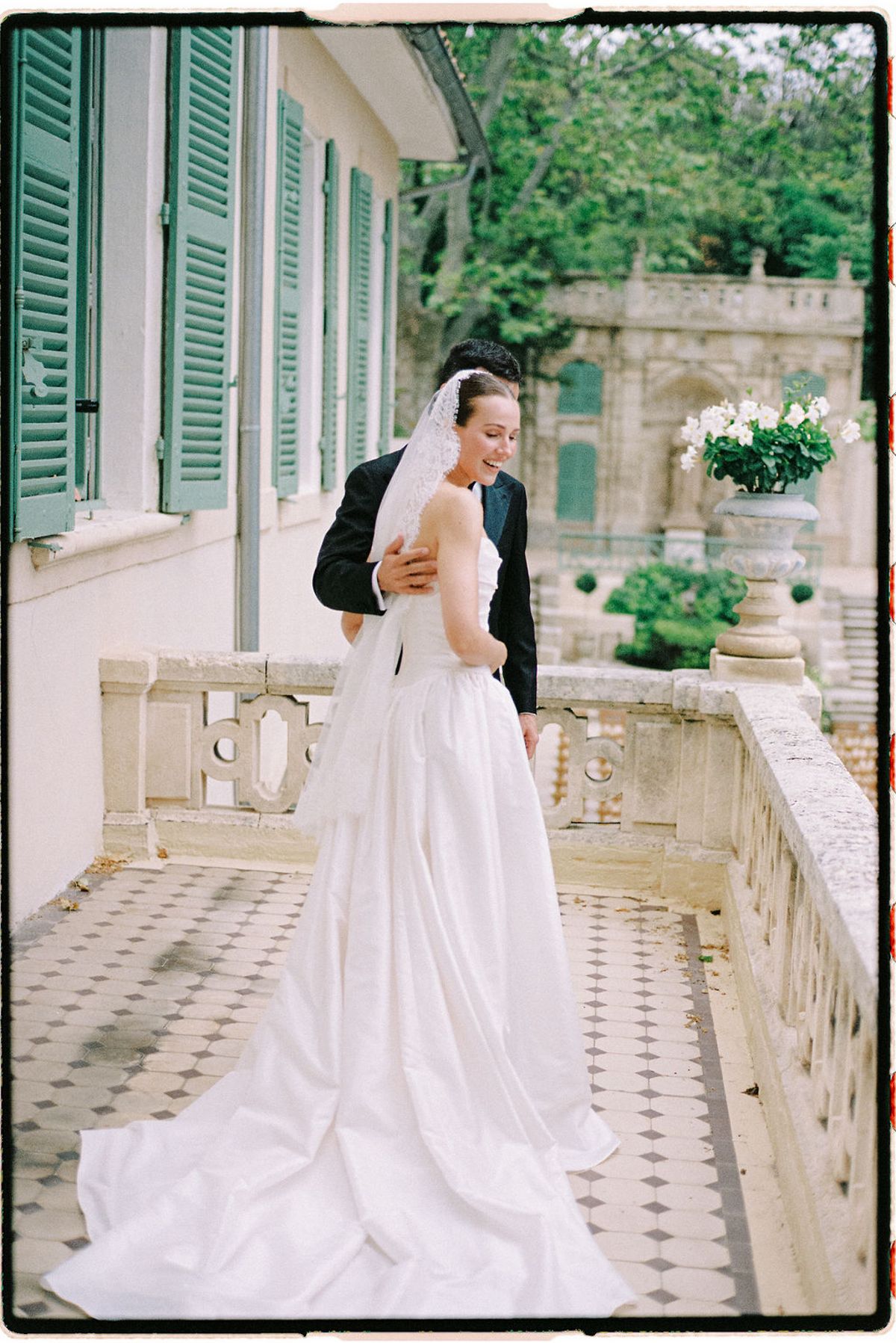 Clara and Constantin stand together on the terrace steps beside floral arrangements