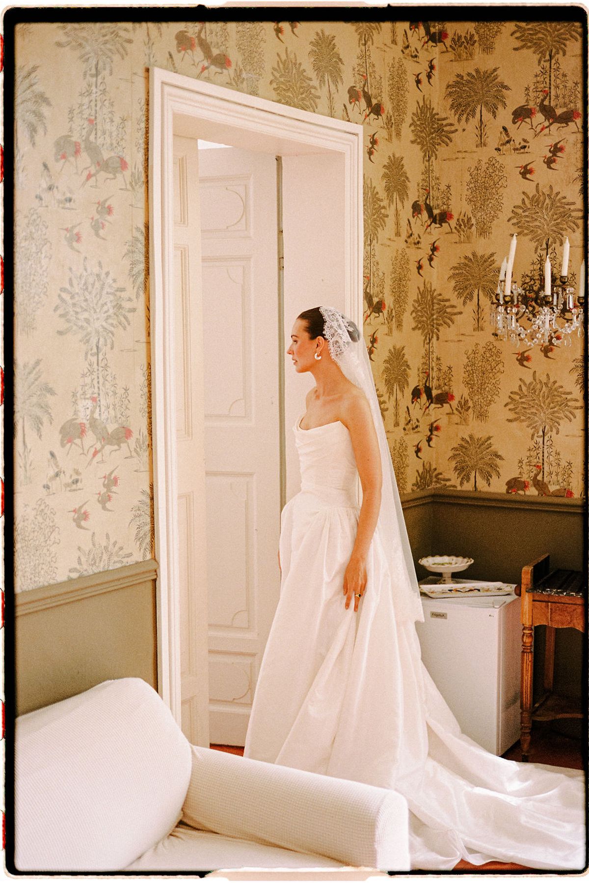 Clara in her veil stands in a room with patterned wallpaper at Bastide de Toursainte