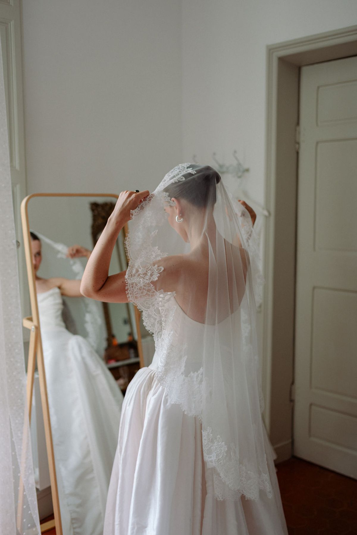 Clara adjusts her veil in the mirror before the ceremony