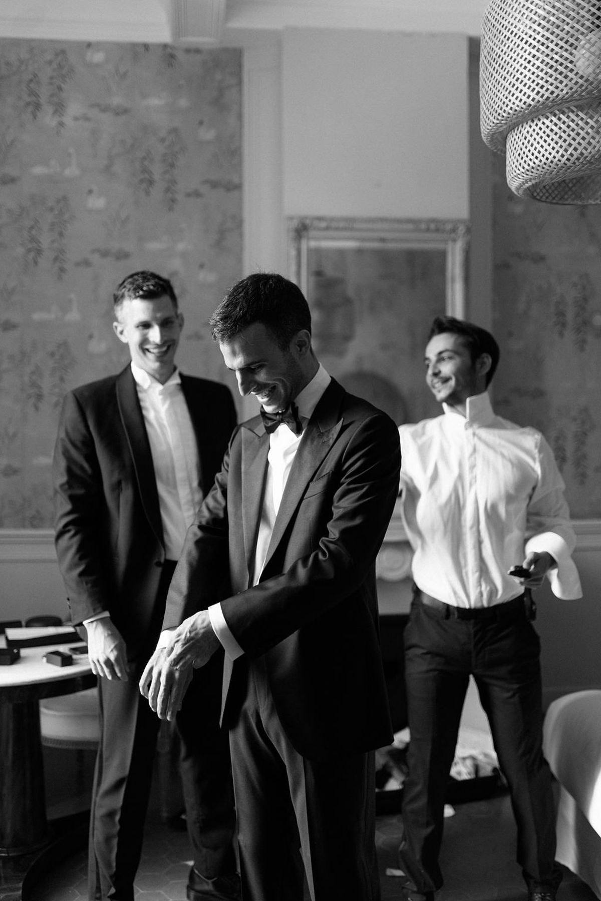 Three groomsmen in black tie share a candid moment together