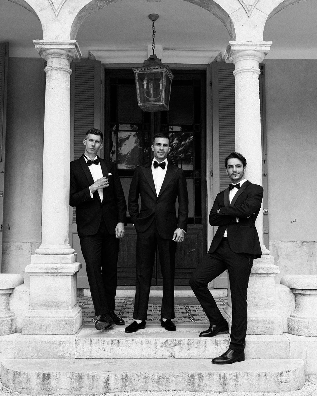 Two groomsmen pose against the columns of Bastide de Toursainte