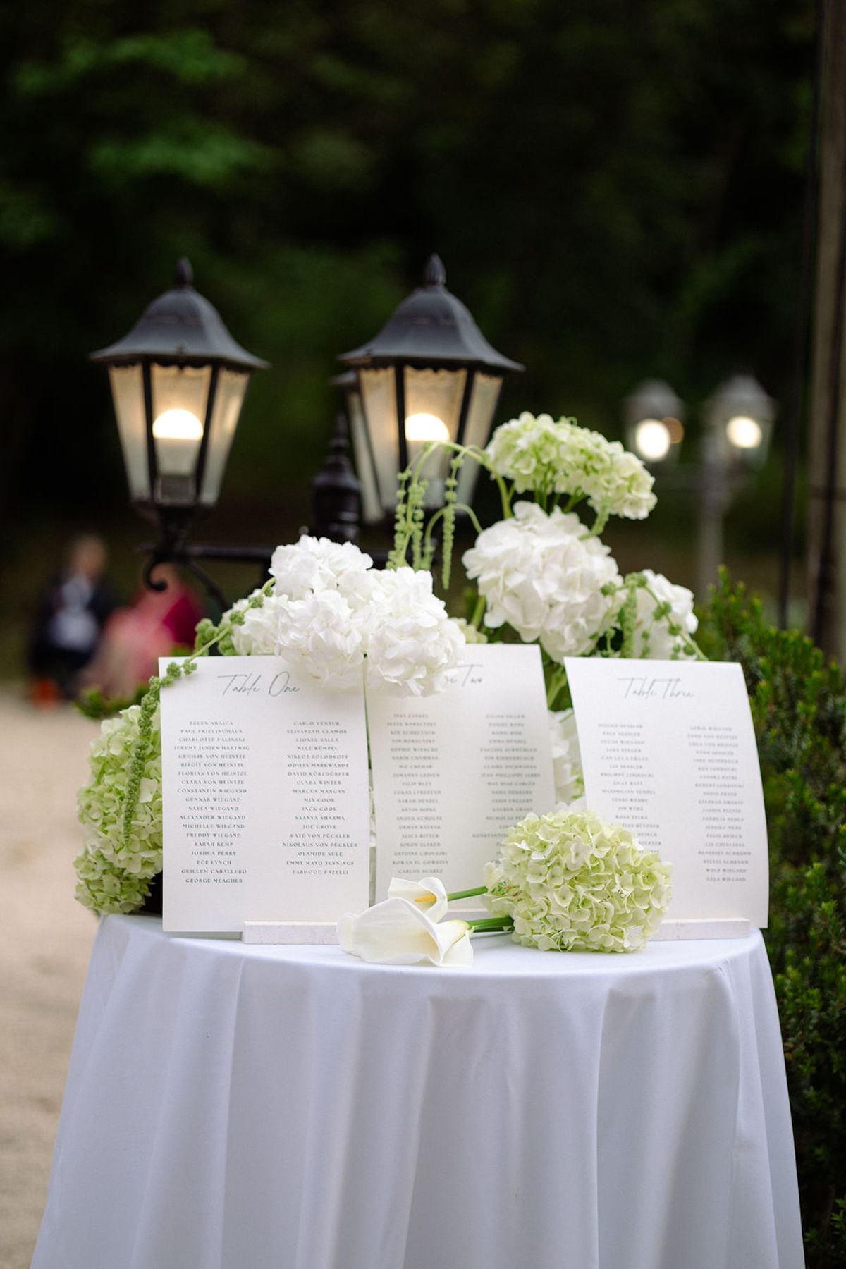 The seating chart displayed among white floral arrangements at the entrance