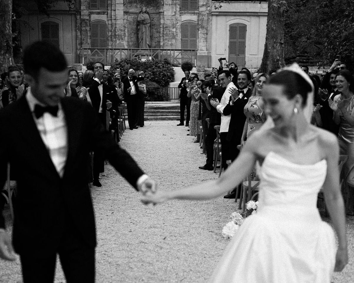 Clara and Constantin walk hand in hand past the seated guests
